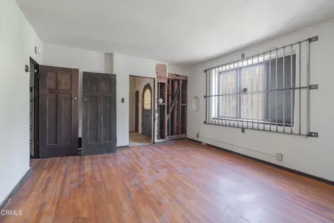 a view of an empty room with wooden floor and a bathroom