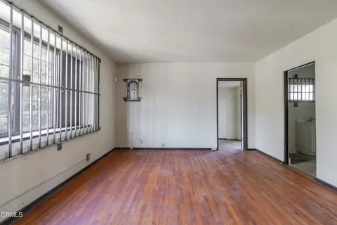 a view of an empty room with wooden floor and closet