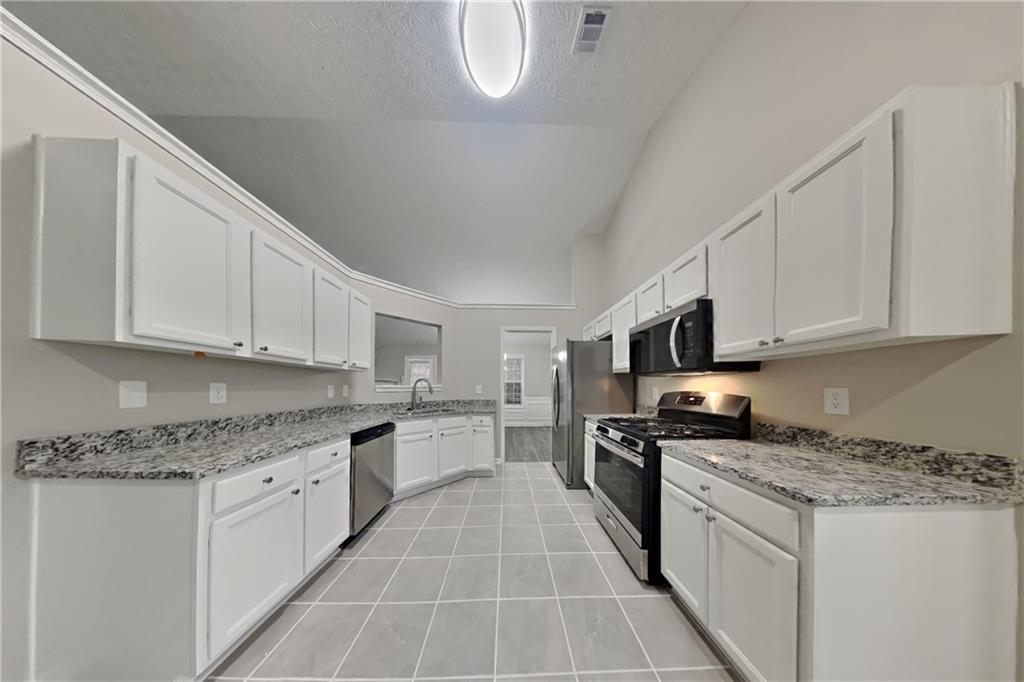 775 James Ridge Drive Lawrenceville, GA 30045 - Photo 4 of 19 a kitchen with stainless steel appliances granite countertop a stove a sink and white cabinets
