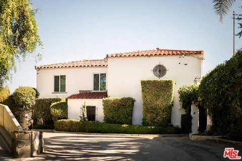 a view of a white house with a large windows and a table and chairs