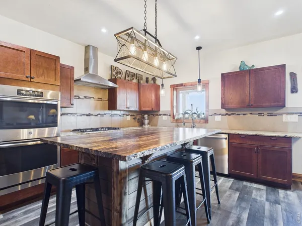 a kitchen with stainless steel appliances granite countertop a table chairs sink and cabinets