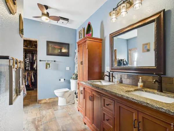 a spacious bathroom with a granite countertop double vanity sink a mirror and a toilet