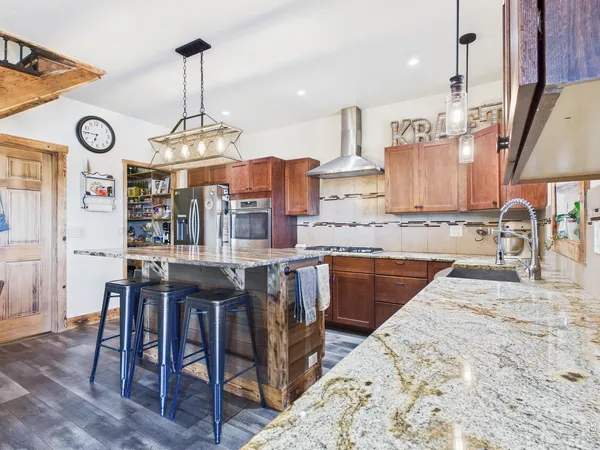 a kitchen with stainless steel appliances granite countertop a sink a stove and a wooden floors