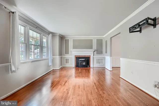 a view of an empty room with wooden floor fireplace and a window