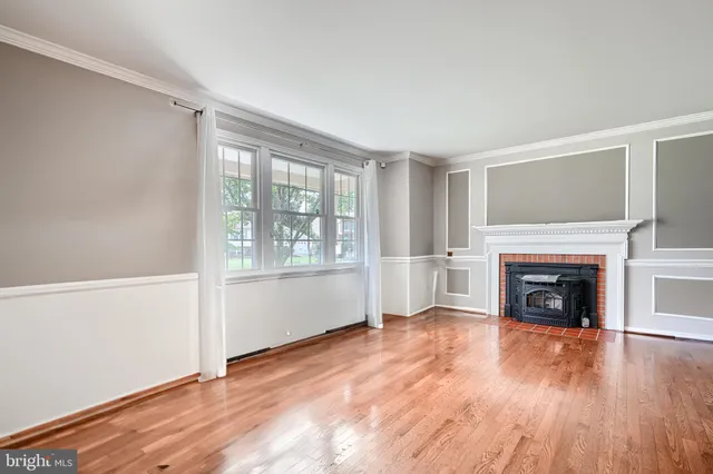 an empty room with wooden floor fireplace and windows