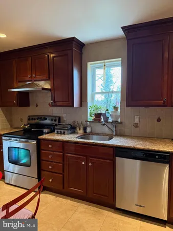 a kitchen with stainless steel appliances granite countertop wooden cabinets a stove a sink and a window