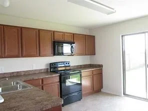 a kitchen with granite countertop a stove top oven microwave and cabinets