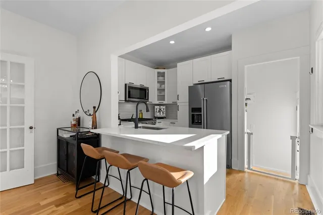 a kitchen with a refrigerator a stove a sink dishwasher a dining table and chairs with wooden floor