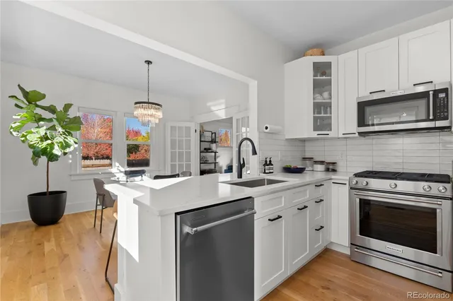 a kitchen with stainless steel appliances a stove a sink dishwasher a microwave oven with a dining table and chairs