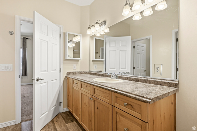 1177 Northfield Road, Unit 26 Cedar City, UT 84721 - Photo 24 of 45 Bathroom featuring a wood-finish double vanity with a light speckled countertop, dual under-mount sinks, and a full-width mirror