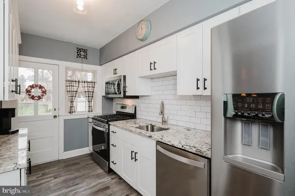a kitchen with stainless steel appliances granite countertop a lot of counter space and wooden floors