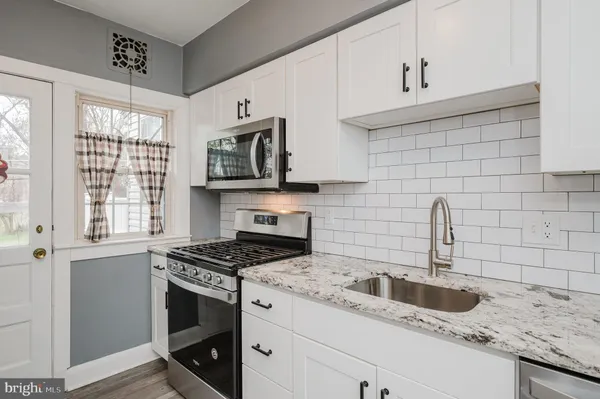 a kitchen with granite countertop a sink a stove and cabinets
