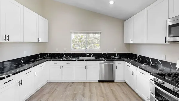 a kitchen with granite countertop white cabinets and black appliances