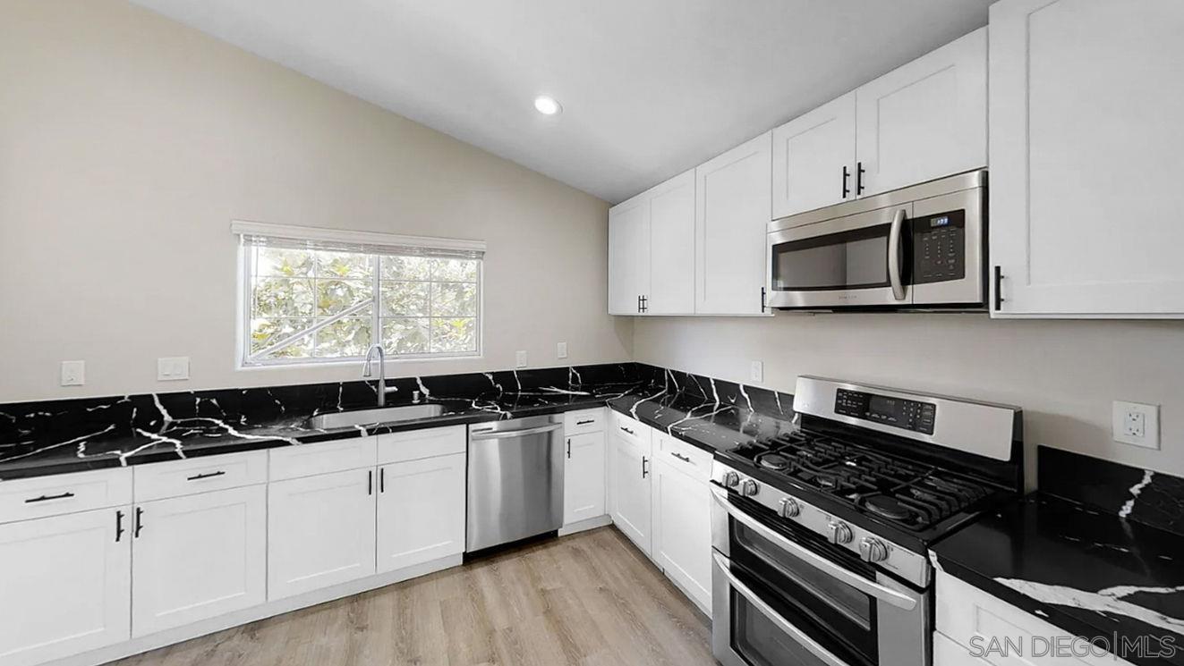 6497 Montezuma Road San Diego, CA 92115 - Photo 4 of 23 a kitchen with granite countertop white cabinets and black appliances