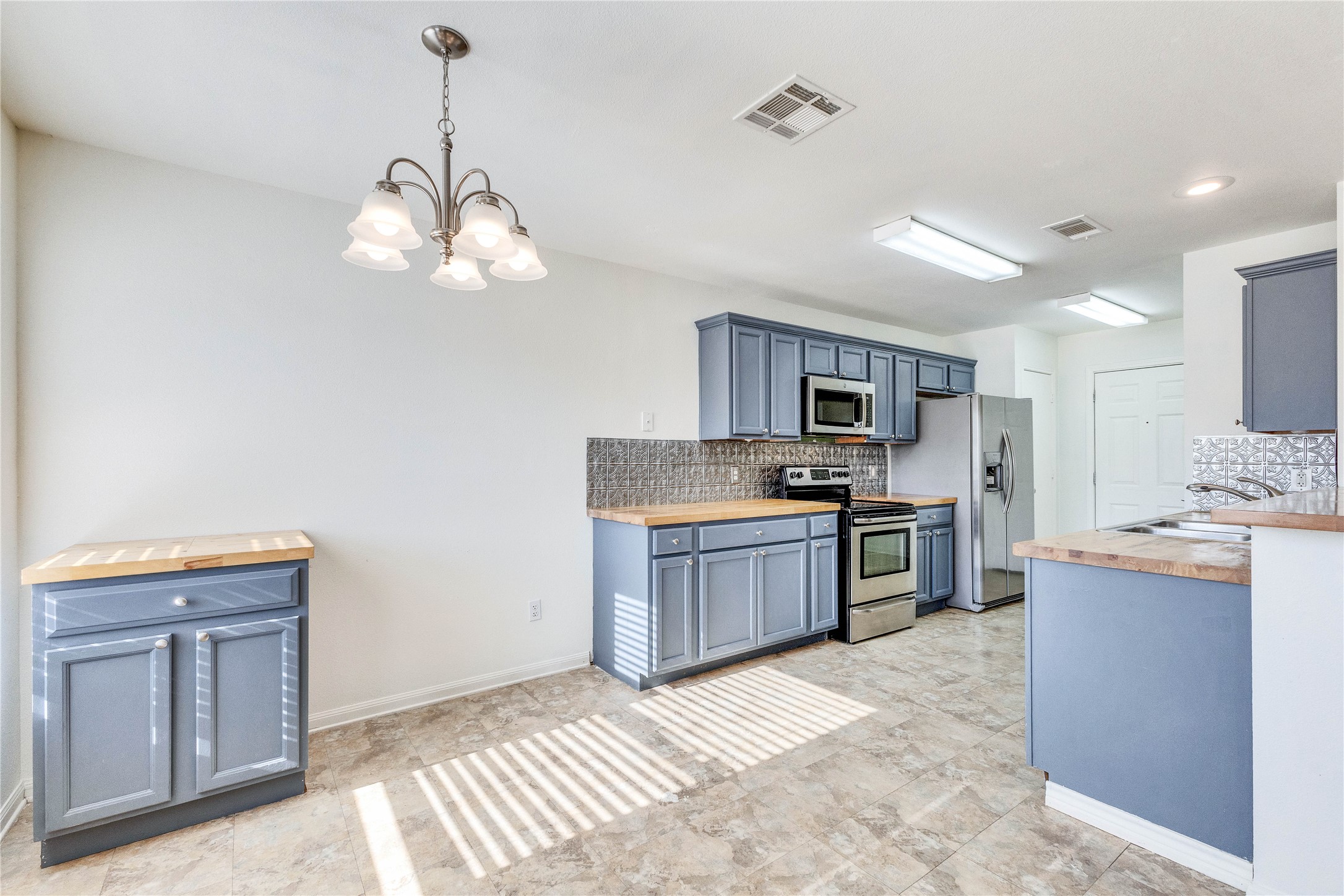 1103 Madison Temple, TX 76504 - Photo 1 of 26 Kitchen with butcher block counters, stainless steel appliances, decorative backsplash, and a chandelier