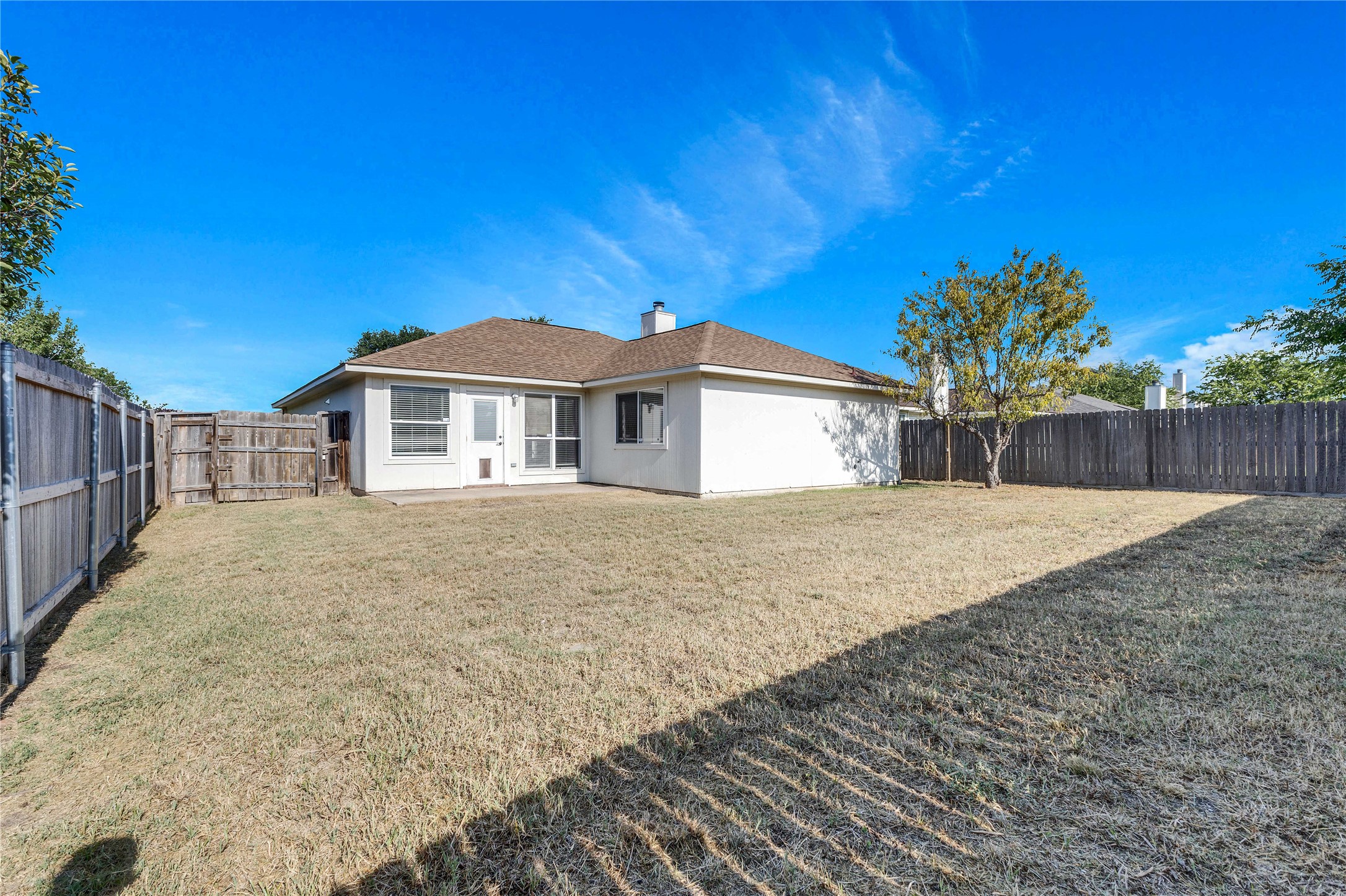 1103 Madison Temple, TX 76504 - Photo 19 of 26 Back of property featuring a chimney, stucco siding, a fenced backyard, a shingled roof, and a patio