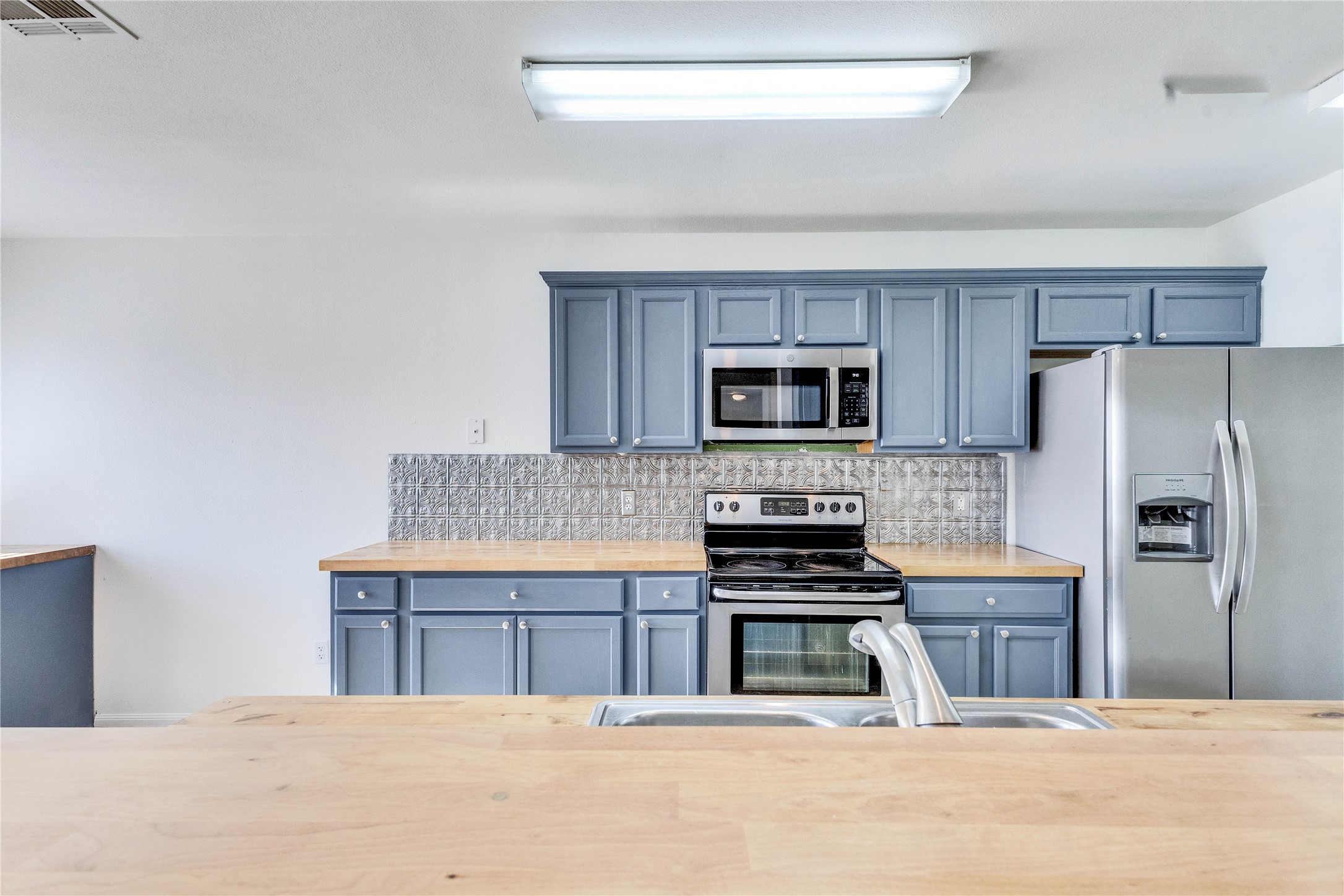 1103 Madison Temple, TX 76504 - Photo 4 of 26 Kitchen featuring stainless steel appliances, tasteful backsplash, and blue cabinets
