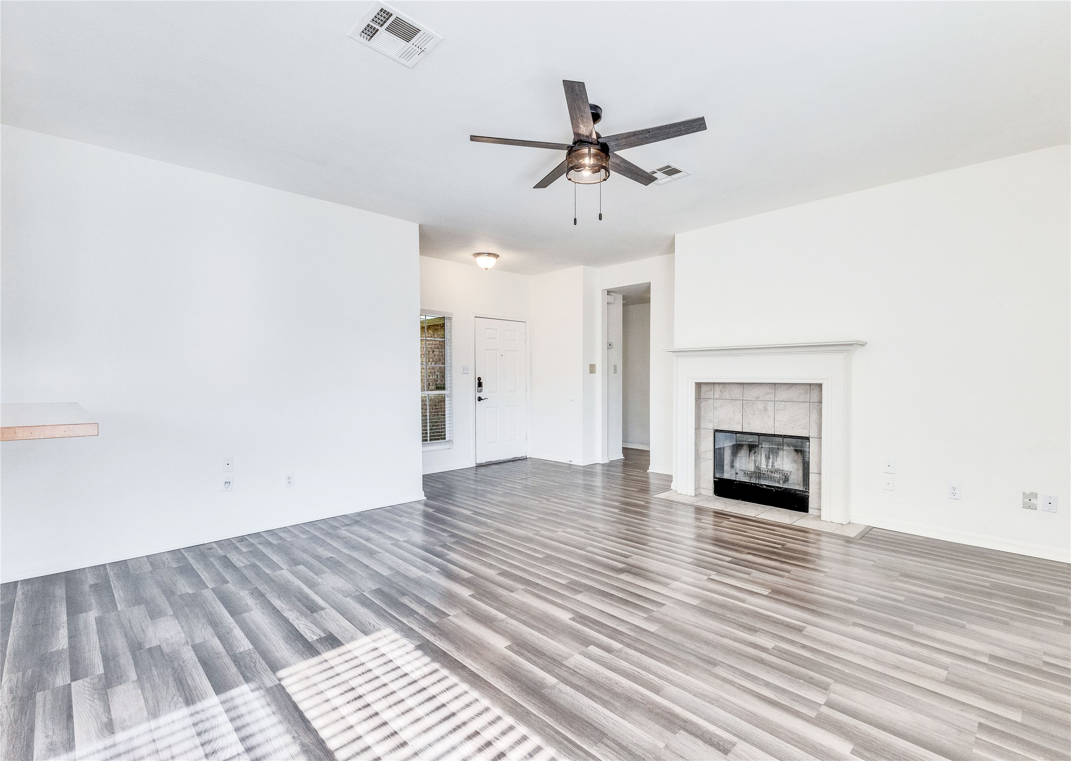 1103 Madison Temple, TX 76504 - Photo 9 of 26 Unfurnished living room with a ceiling fan, light wood-style floors, and a fireplace