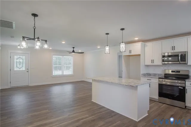 a kitchen with stainless steel appliances granite countertop a stove top oven a sink dishwasher and a refrigerator with wooden floor