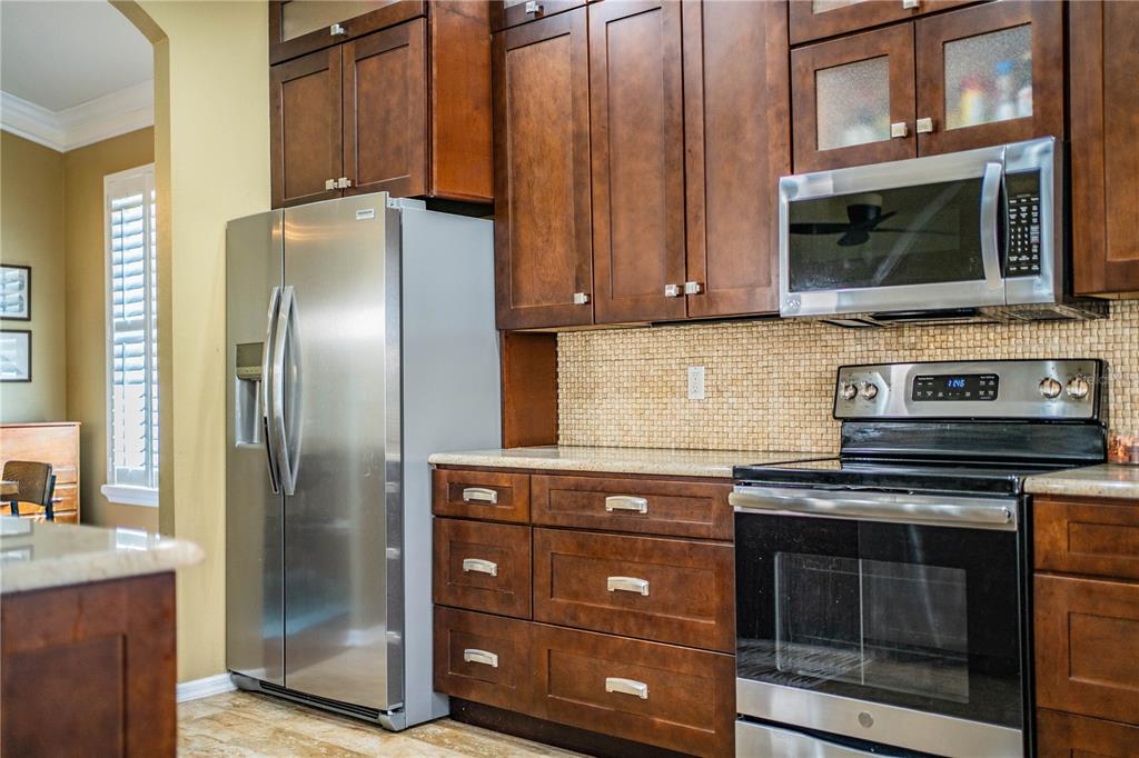 3234 Stonebridge Trail Valrico, FL 33596 - Photo 10 of 34 a kitchen with granite countertop a refrigerator stove and microwave