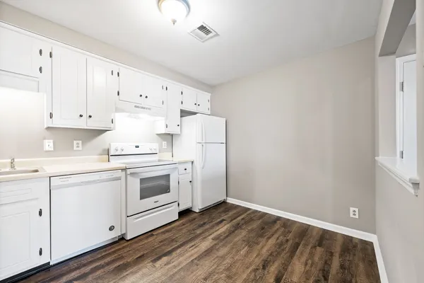 a kitchen with cabinets appliances and wooden floor