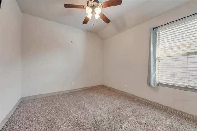 an empty room with a window and a chandelier fan