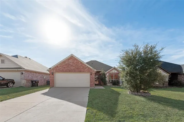 a front view of a house with a garden and trees