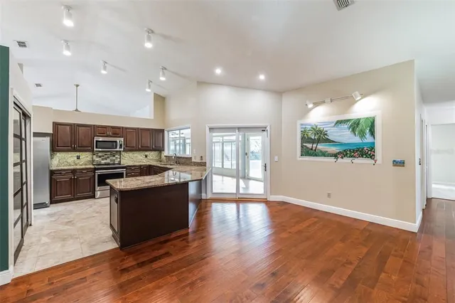 a large kitchen with stainless steel appliances granite countertop a stove and a wooden floors