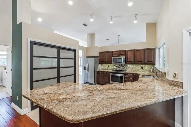 a kitchen with stainless steel appliances granite countertop a sink a stove and a microwave