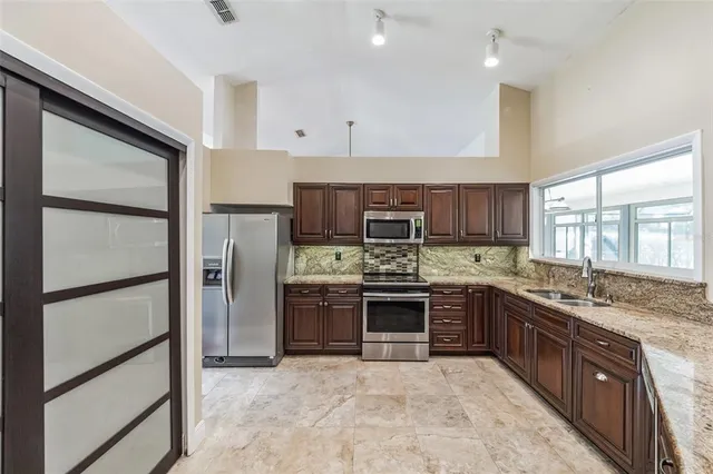 a large kitchen with stainless steel appliances granite countertop a stove a sink and a refrigerator