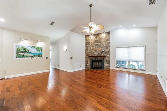 a view of an empty room with wooden floor fireplace and a window