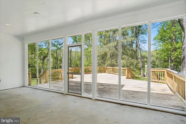 a view of an empty room with wooden floor and door