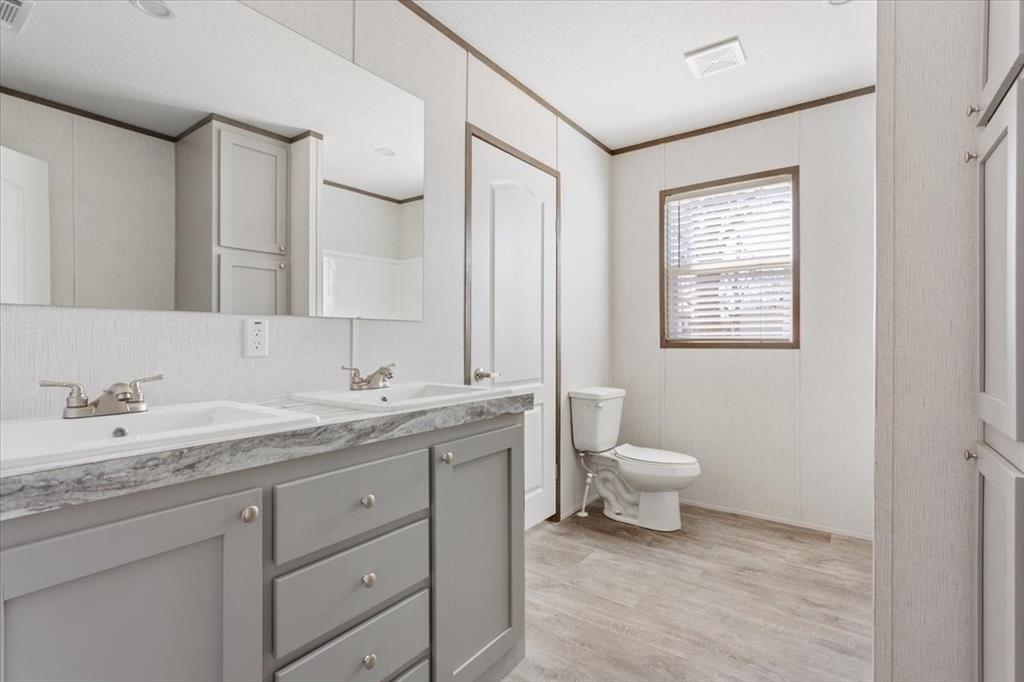 201 North Carpenter Street Mart, TX 76664 - Photo 21 of 30 a bathroom with a granite countertop toilet a sink and a mirror