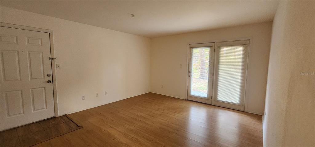 232 Afton Square, Unit 108 Altamonte Springs, FL 32714 - Photo 19 of 26 an empty room with wooden floor and windows with curtains