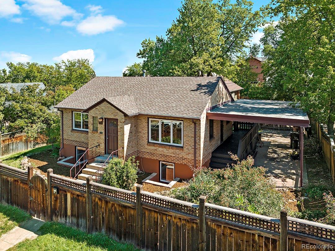 a view of a house with wooden fence next to a yard