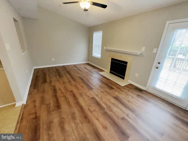 a view of an empty room with wooden floor and window