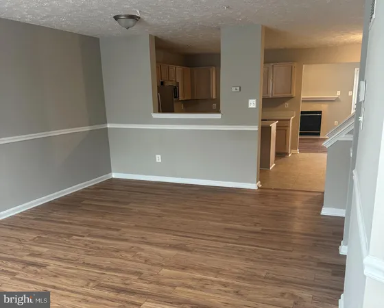 an empty room with wooden floor and a kitchen