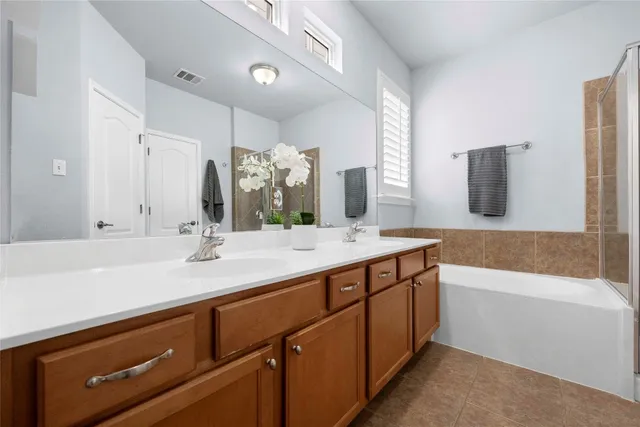 a bathroom with a sink double vanity granite tub shower and a mirror