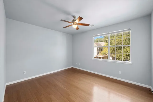 an empty room with windows and fan