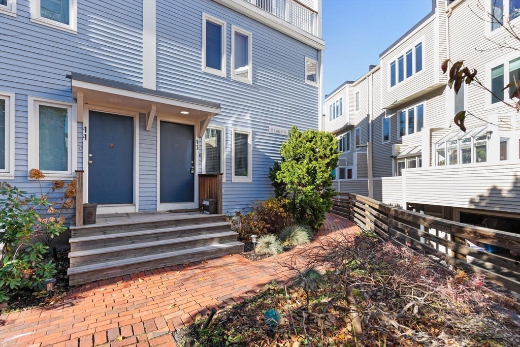 676 Huron Avenue, Unit 43 Cambridge, MA 02138 - Photo 2 of 20 a view of a house with potted plants and a bench in front of it