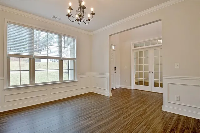 a view of an empty room with wooden floor and a kitchen