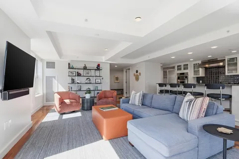 a living room with furniture a flat screen tv and kitchen view