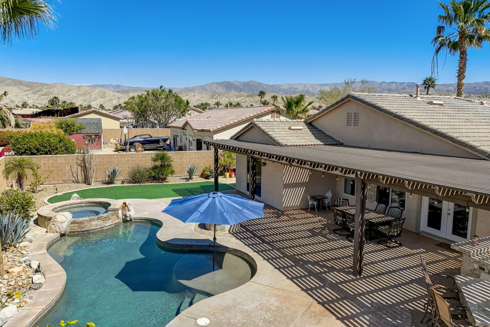41163 Morris Street Indio, CA 92203 - Photo 65 of 83 a view of a patio with couches table and chairs under an umbrella with a fire pit
