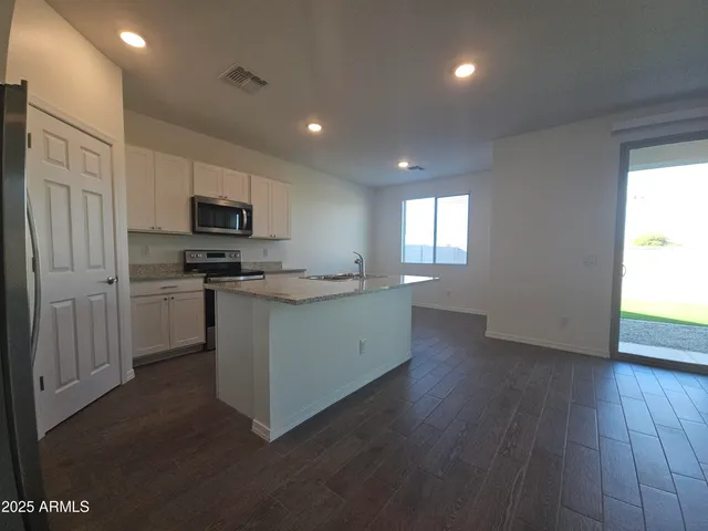 a kitchen with kitchen island granite countertop a stove top oven a sink a counter space and cabinets