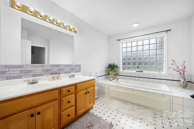 a bathroom with a tub a sink and mirror