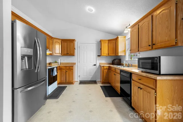 a kitchen with granite countertop a refrigerator and a stove top oven