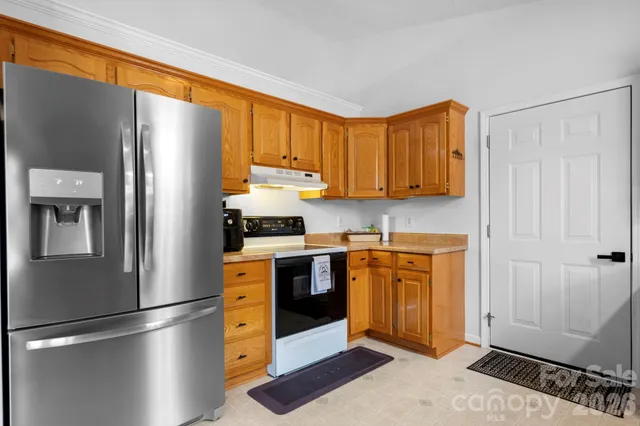 a kitchen with stainless steel appliances granite countertop a refrigerator a stove and a sink