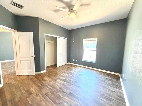 an empty room with chandelier fan and windows