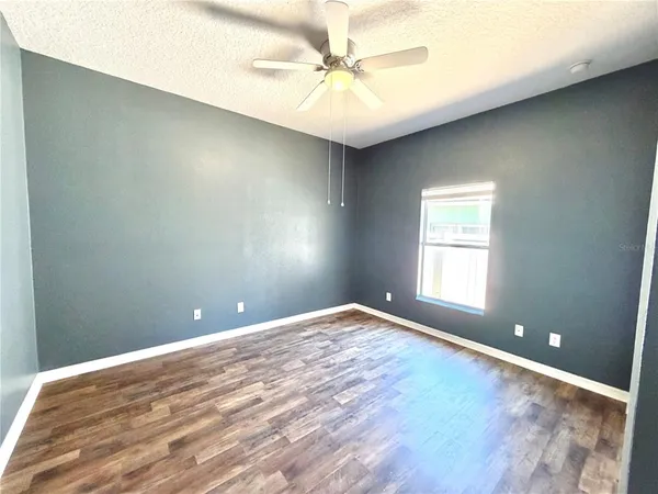 an empty room with a window and a ceiling fan