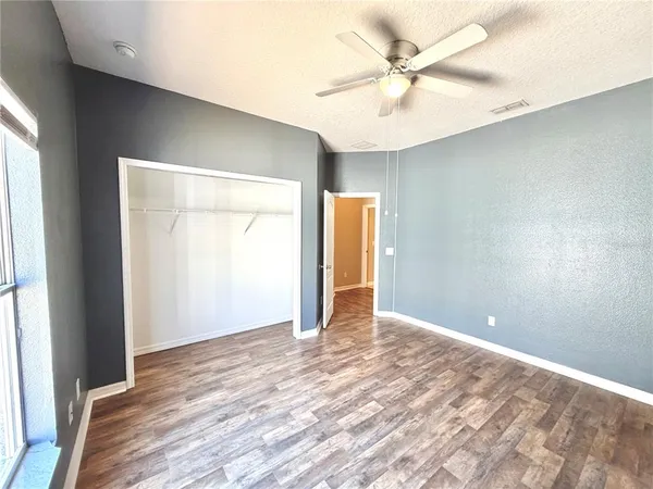 an empty room with wooden floor and a ceiling fan